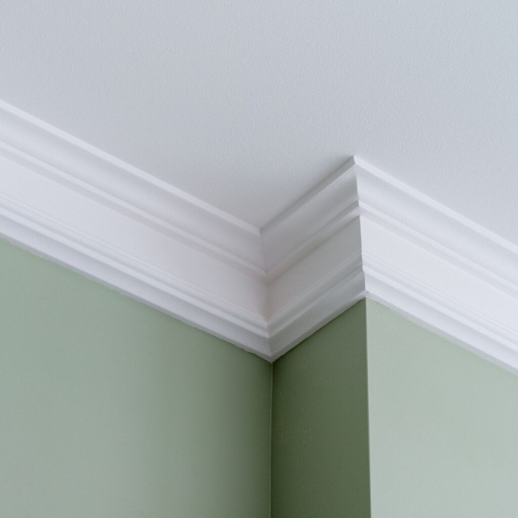 close up shot of crown molding installed on green painted wall