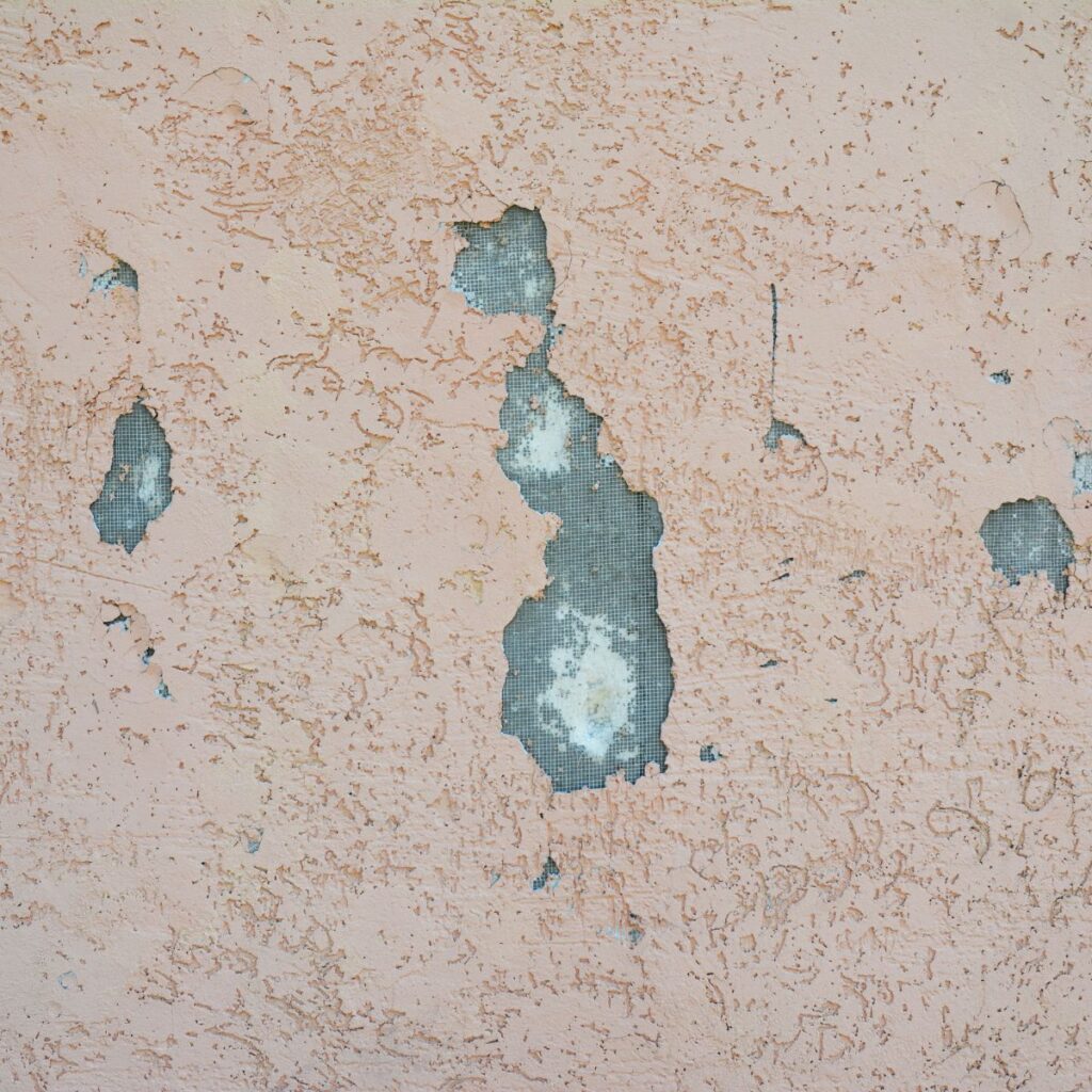 close up of cracks and holes in exterior stucco