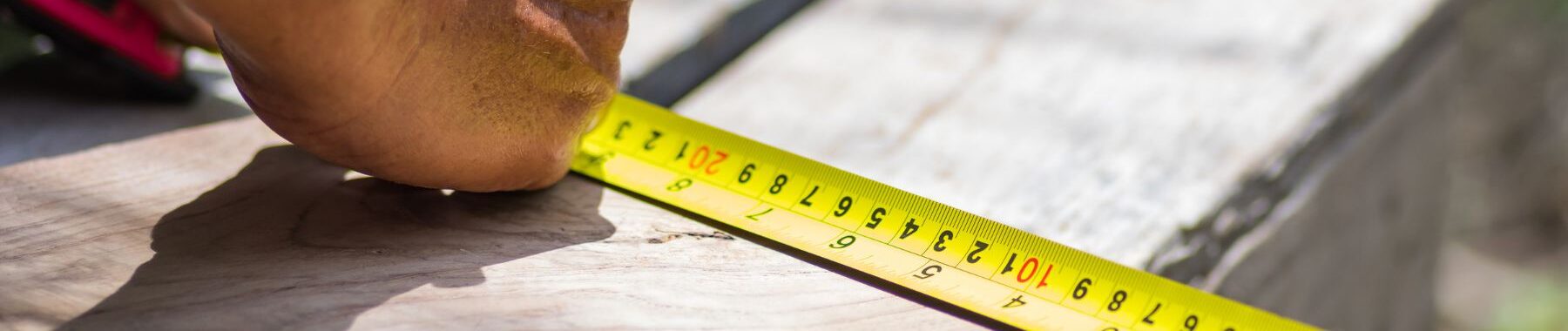 man using a measuring tape to make a measurement with a pen