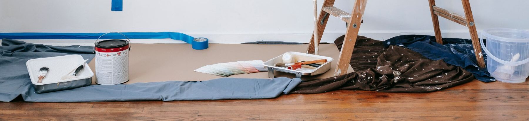 dropcloths on the ground with painting supplies for an interior painting job