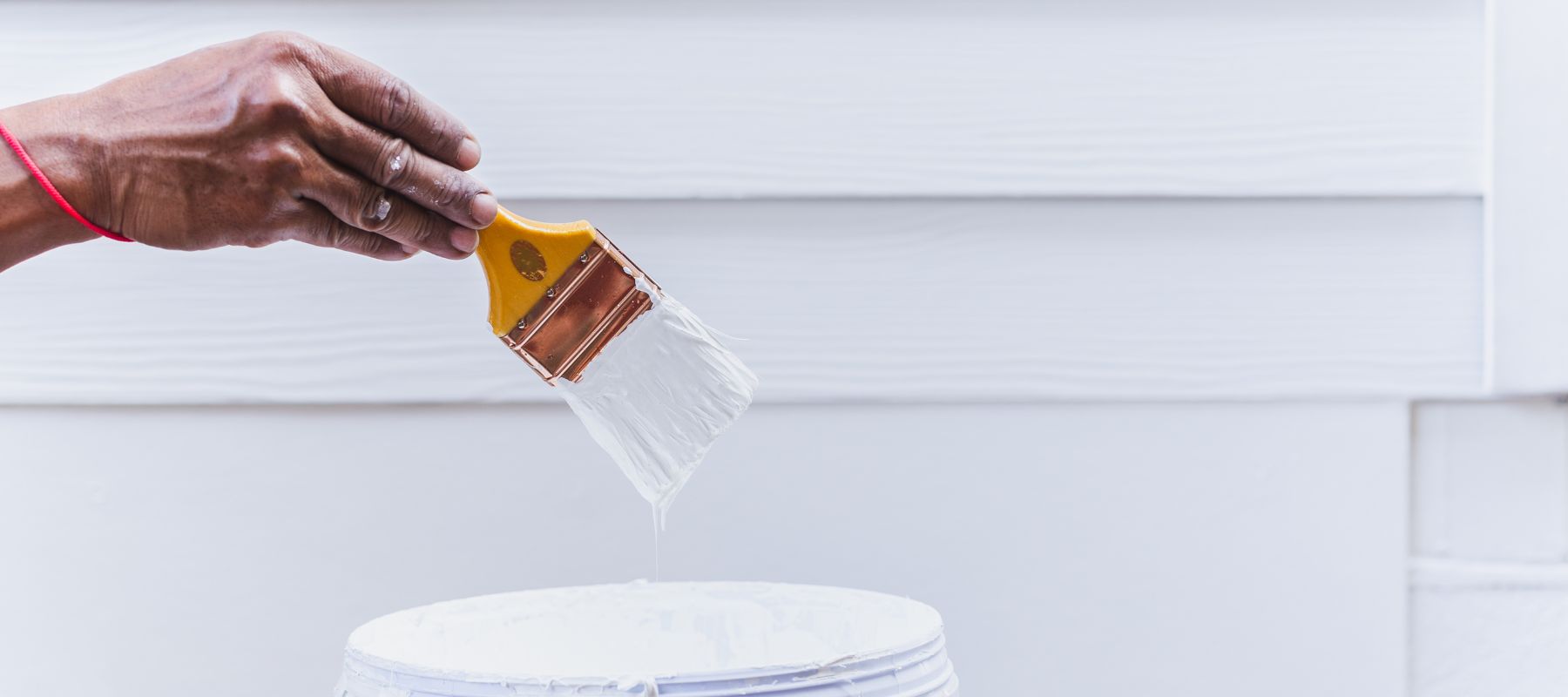 using a brush to paint siding white