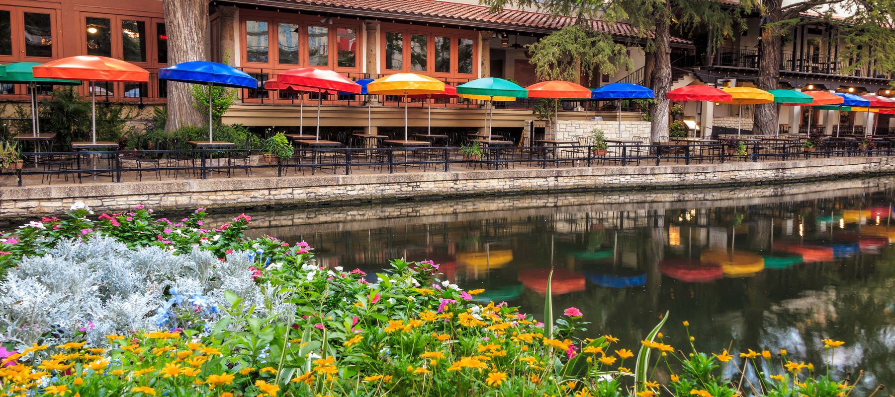 downtown san antonio riverwalk showing the water and colorful umbrellas at a local restaurant